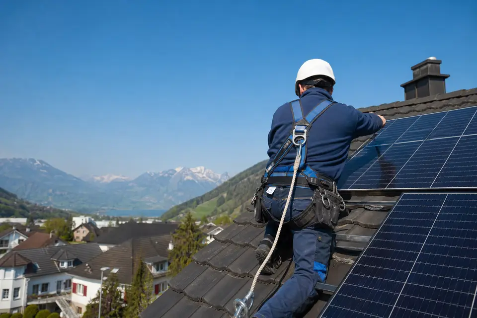 Installateur posant des panneaux photovoltaïques sur une toiture, vu de dos
